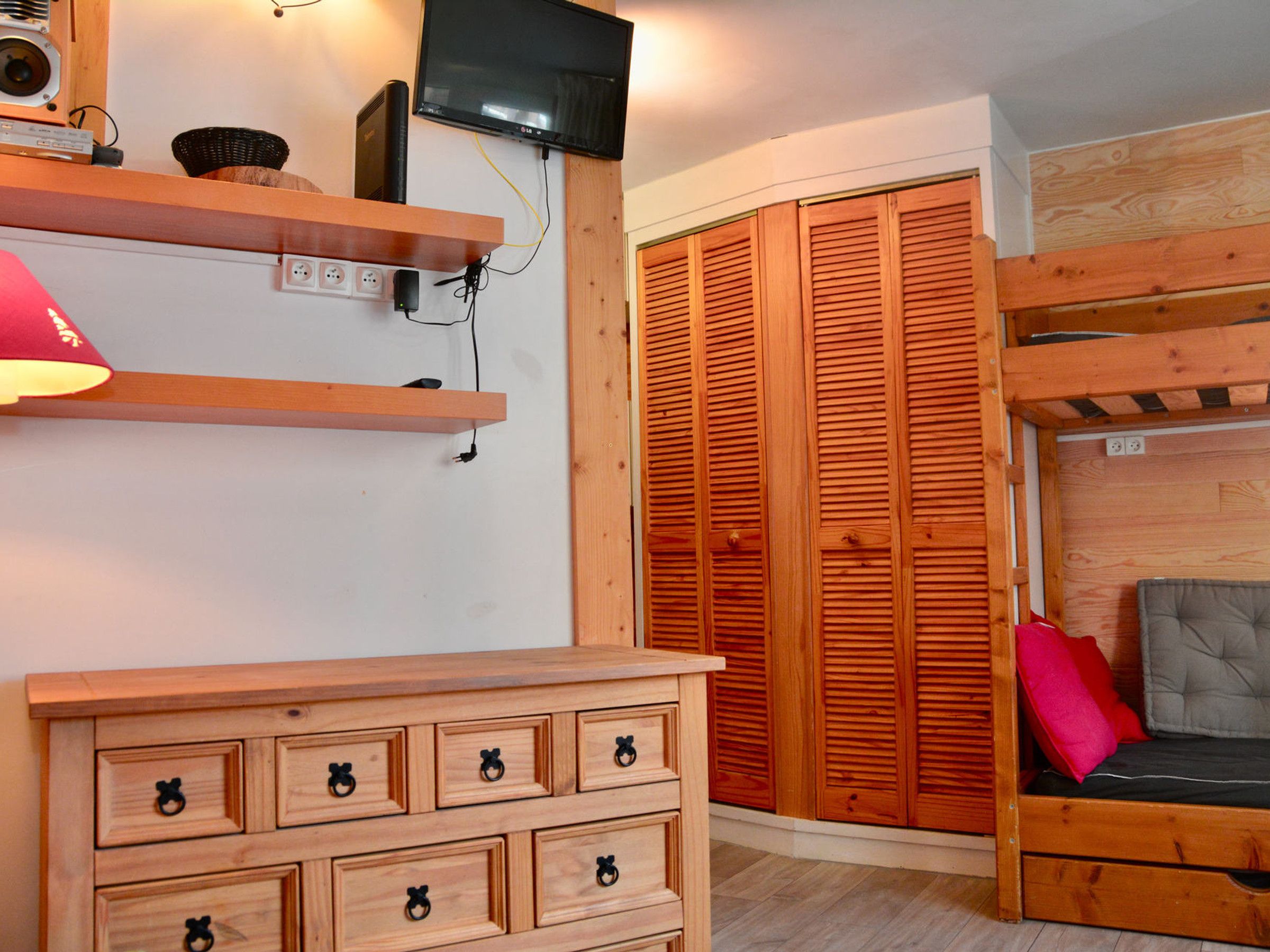 Una habitación con un aparador de madera, un televisor montado en la pared y un armario de madera.
