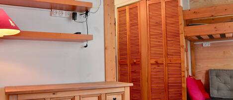 Una habitación con un aparador de madera, un televisor montado en la pared y un armario de madera.