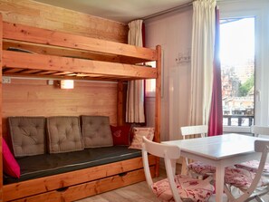 A bunk bed with a cushioned bench, a white table, and chairs with patterned cushions. - Studio for 3 guests near children (Avoriaz)
