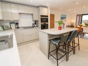A modern kitchen with a central island, bar stools, and a dining area with a table and chairs.