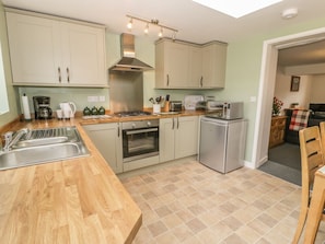 A kitchen with a wooden countertop, stainless steel appliances, and light green cabinets.