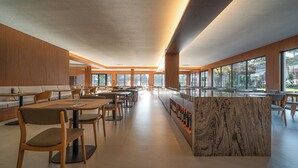 Un café espacioso con mobiliario de madera, ventanas amplias y una barra de mármol.