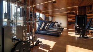 Un gimnasio con cintas de correr, máquinas de pesas y una máquina de remo.