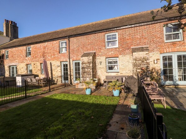 A brick building with a stone facade, a small garden with potted plants, and a metal fence.