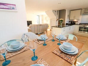 A dining area with a wooden table set for four, surrounded by chairs.