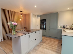 A modern kitchen with a central island, grey cabinets, and a wooden accent wall.