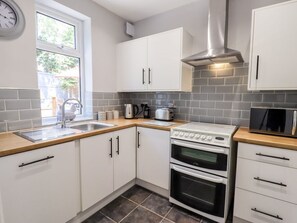 A modern kitchen with white cabinets, a stainless steel range hood, a microwave, and a double oven. - 13 The Crescent, Rhos-On-Sea (Bae Colwyn)