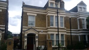 A Victorian-style house with a prominent entrance, a brick facade, and a gated driveway. - Peaceful 1-bedroom apartment in welcoming London neighborhood (London)