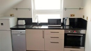A compact kitchen with a dishwasher, microwave, toaster, and oven. - Peaceful 1-bedroom apartment in welcoming London neighborhood (London)