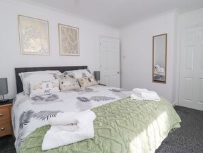 A bedroom with a bed, pillows, a bedside table, a mirror, and artwork on the wall. - Ted's Cottage, Skipton 2 bed (Skipton)
