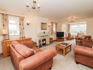 A living room with a fireplace, sofas, a television, and a view of the outdoors. - Jess Cottage, Skipton (Skipton)