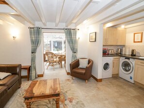 A living room with a sofa, armchair, coffee table, and a view to a dining area. - The Old Barn, Ruthin (Mold)