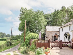 A rural setting with a stone building, a paved driveway, and a gated entrance. - The Old Barn, Ruthin (Mold)