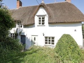 A white house with a thatched roof, a small window, and a door.