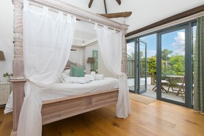 A four-poster bed with white linens, a wooden headboard, and a canopy. - Wesley Barn, Cubert, Cornwall. (Newquay)