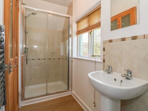 A bathroom with a glass shower enclosure, a sink, and a window with blinds. - The Roost, East Tytherley (Salisbury)