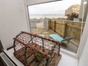 Una habitación con vista a la playa, una valla de madera y mobiliario exterior.