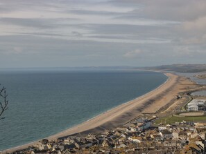 A coastal town with a beach, houses, and a large body of water. - Fisherman's Rest, Wyke Regis (Weymouth)