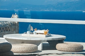 A round table with a tray, wicker ottomans, and a view of the sea. - Mykonos Cloud White Villa (Mykonos)