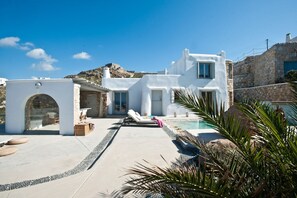 A modern white villa with a swimming pool, stone walls, and a view of the sea. - Mykonos Cloud White Villa (Mykonos)