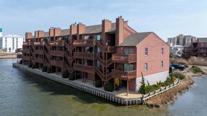 Un hotel frente al agua con varios balcones, un muelle y vistas despejadas al agua.