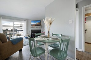 A living room with a round table, green chairs, a sofa, and a fireplace. - Sunset Landing, peaceful water views and front-row seats to some of Ocean City’s stunning sunset (Ocean City)
