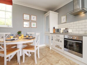 A kitchen with white cabinets, a microwave, an oven, and a dining table with chairs. - The Tack Room, Lydney (Lydney)