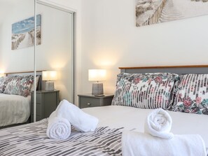 Une chambre d’hôtel avec un lit, deux tables de chevet avec des lampes, un miroir et un tableau au mur.