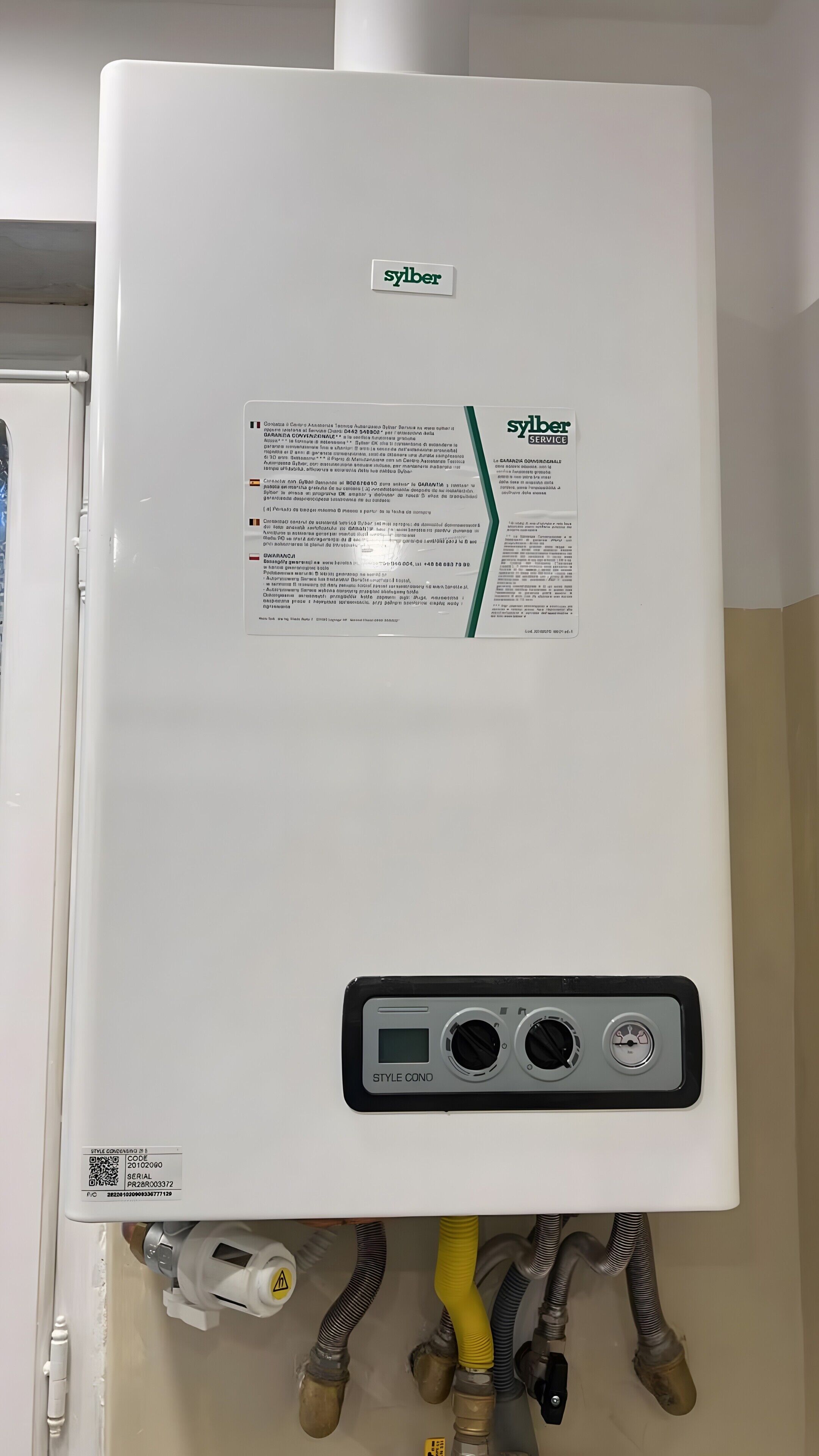 A white water heater with a service label, control panel, and visible plumbing connections.