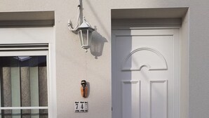 A white door with a number plaque, a window with vertical blinds, and a wall-mounted light fixture. - 200 meters from the streetcar stop, room with shared bathroom, quiet! (Eysines)