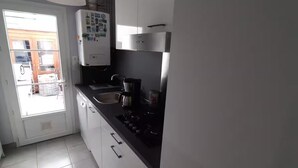 A kitchen with white cabinets, a black countertop, a stove, and a hanging light fixture. - 200 meters from the streetcar stop, room with shared bathroom, quiet! (Eysines)