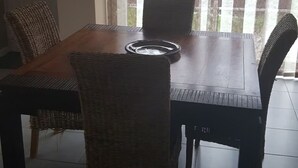 A dining area with a wooden table and wicker chairs, a vase on a shelf, and a view through striped curtains. - 200 meters from the streetcar stop, room with shared bathroom, quiet! (Eysines)