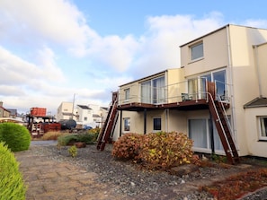 Un bâtiment à deux étages doté d’un balcon, d’un escalier et d’un petit jardin.