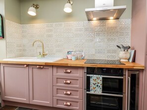A kitchen with a sink, stove, oven, and cabinets.