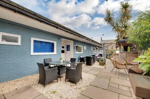 A blue building with outdoor seating, a patio, and a wooden fence.