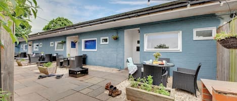 A blue building with outdoor seating, a patio, and hanging plants.