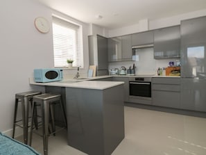 A modern kitchen with a central island, stainless steel appliances, and a window with blinds.