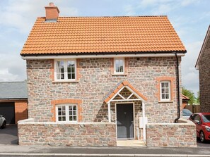 A stone house with a tiled roof, a central door, and two windows on the upper floor.