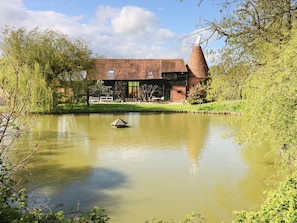 A building with a brick exterior, a large chimney, and a pond in front.