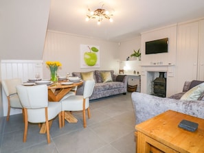 A modern living room with a dining area, a fireplace, and a flat-screen TV mounted above it.