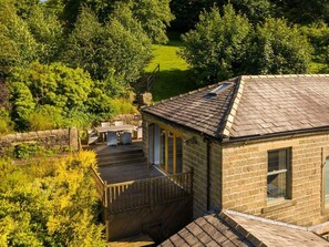 A stone building with a deck, a window, and a view of a green landscape. - Moorlands Manor, in Foulridge. (Colne)