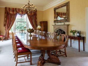 A formal dining room with a large wooden table, red cushioned chairs, a chandelier, a fireplace, and a large mirror on the wall. - Moorlands Manor, in Foulridge. (Colne)