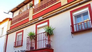 Un immeuble doté de nombreux balcons, de fenêtres avec des barreaux en métal et de plantes en pot sur les balcons.