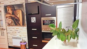 Une cuisine équipée d’un four encastré, d’un four à micro-ondes, d’une cuisinière et d’une petite poubelle.