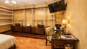 Une chambre d’hôtel comprenant un lit, un bureau avec une lampe, un téléviseur fixé au mur et une armoire avec des cintres.
