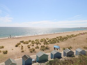 A beach with a row of beach huts, a sandy beach, and the sea.