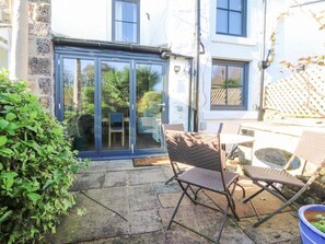 A patio with stone flooring, a glass door leading to a room, and wicker furniture.