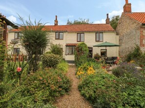 A traditional house with a garden pathway leading to a patio area.
