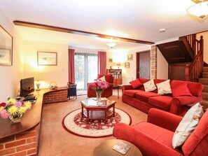A living room with a red sofa, a coffee table, and a fireplace. - Walnut Tree Cottage, Catfield (Great Yarmouth)
