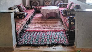 Ein gemütliches Zimmer mit einer Sofagarnitur, einem runden Tisch und einem gemusterten Teppich.